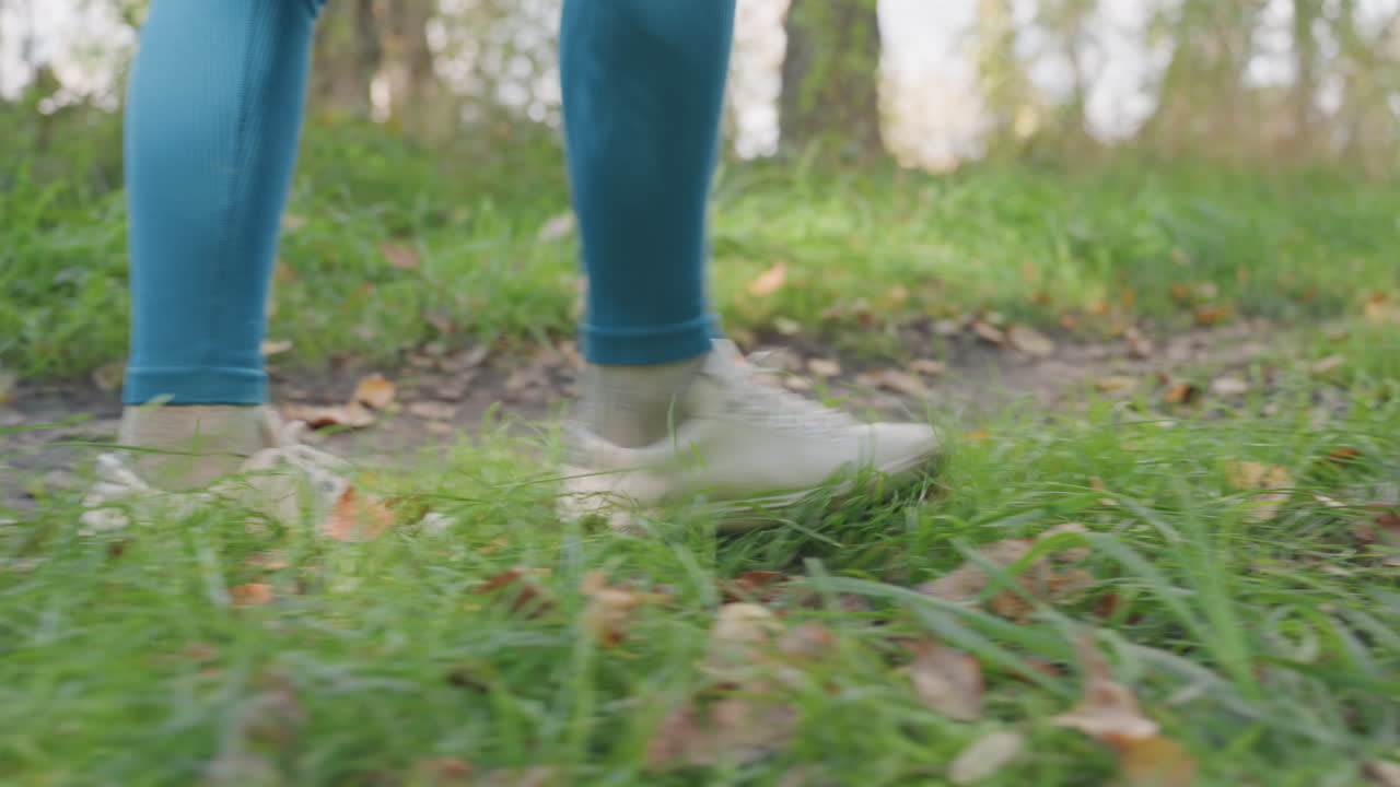 Woman hikes peacefully. Woman strolling through lush forest. Serene woman moves steadily through leafy woodland pathway. Peaceful lady advances quietly on grassy trail toward sheltered camping spot