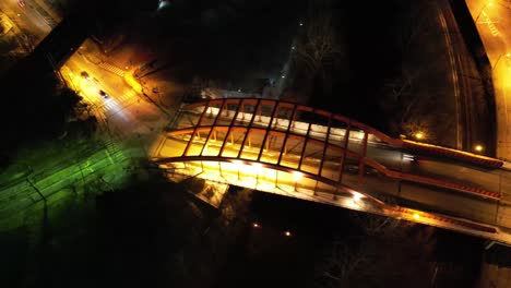 a rotating aerial timelapse over a glowing pedestrian bridge in youngstown, ohio at night, showcasing vivid lighting and motion blur from traffic below.