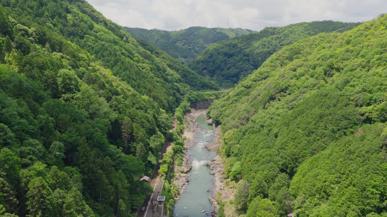 Aerial drone fly above Arashiyama Clean Japanese River in the middle of Forested mountain Landscape of Kyoto
