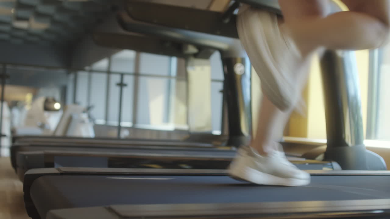 Legs of Woman Running on Treadmill in Gym