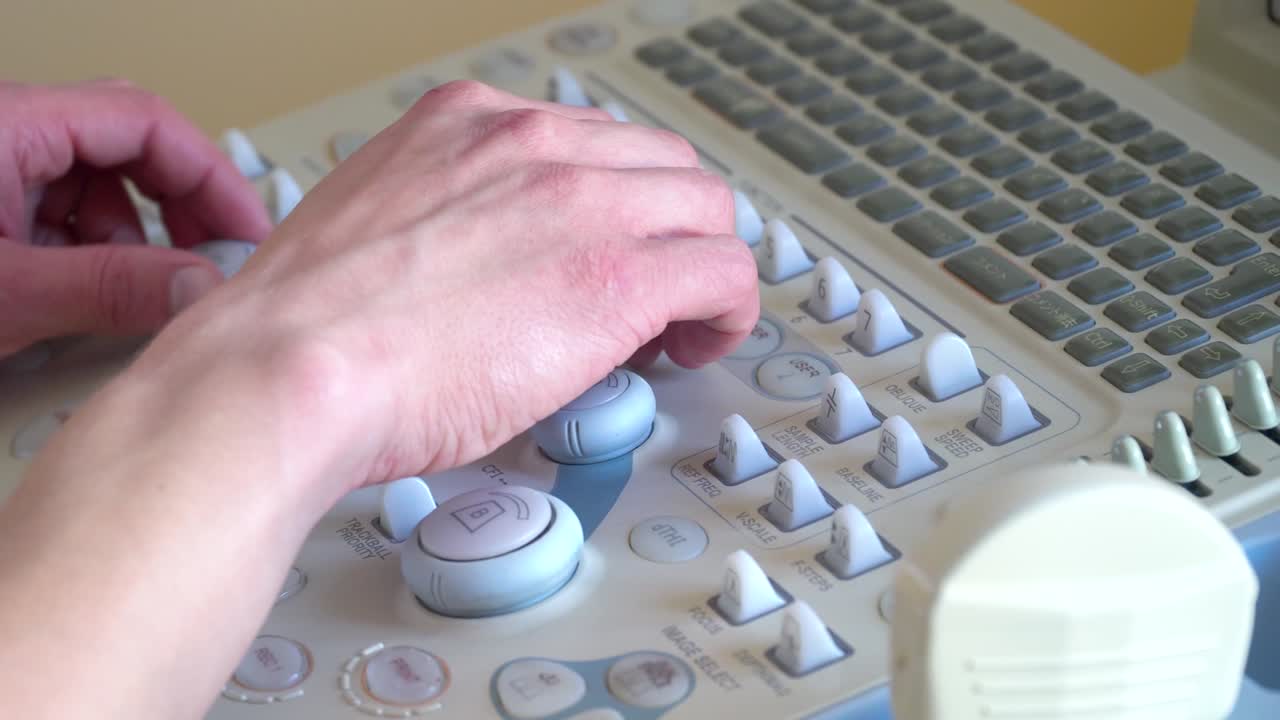 Close up of hands of young doctor working on ultrasound device
