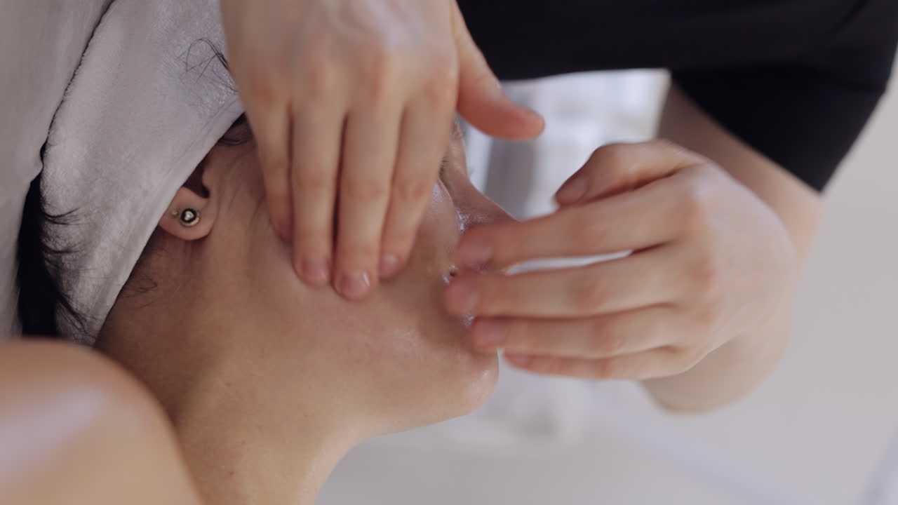 코스메톨로지 테라피스트는 여성이 휴식을 취하는 스파에서 손으로 얼굴 마사지를 할 수 있습니다.