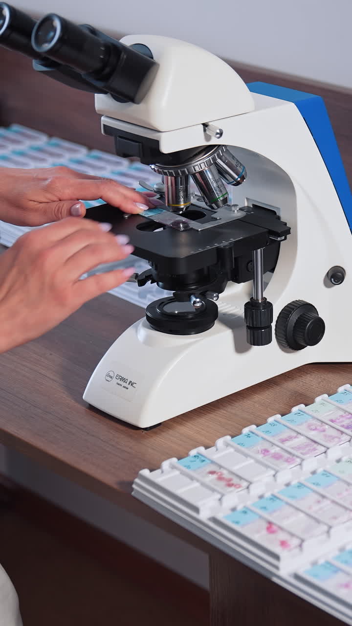 Doctor during biochemical analysis. Drop of samples between two microscope slides. Vertical video