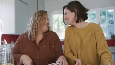 Glückliches-Kaukasisches-Lesbisches-Paar,-Das-Brot-Schneidet-Und-Essen-In-Der-Küche-Zubereitet