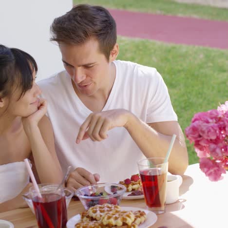 couple talking at breakfast table outside