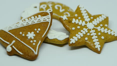 Zoomed-out-pastry-gingerbread-with-white-decoration-on-top-in-various-shapes-lying-on-top-of-each-other-on-a-white-background