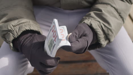 close up on man’s hands checking a pile of usd cash