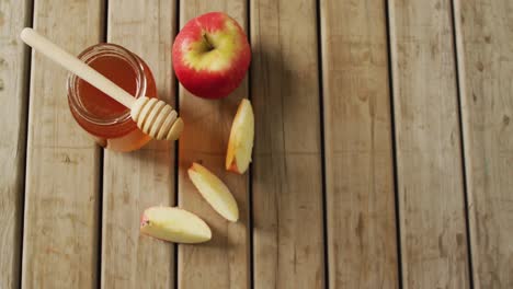 video de miel en frasco y manzanas y rebanadas de manzanas tiradas en una superficie de madera