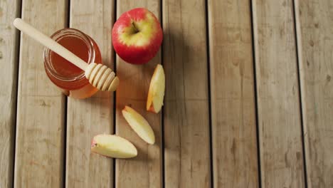 video of honey in jar and apple and apple slices lying on wooden surface