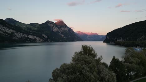 Drohnenflug-über-Grüne-Wiese-Und-Bäume-Gegen-Den-See-Und-Die-Berge-Mit-Wunderschönem-Himmel-Am-Ufer-Des-Walensees,-Schweiz