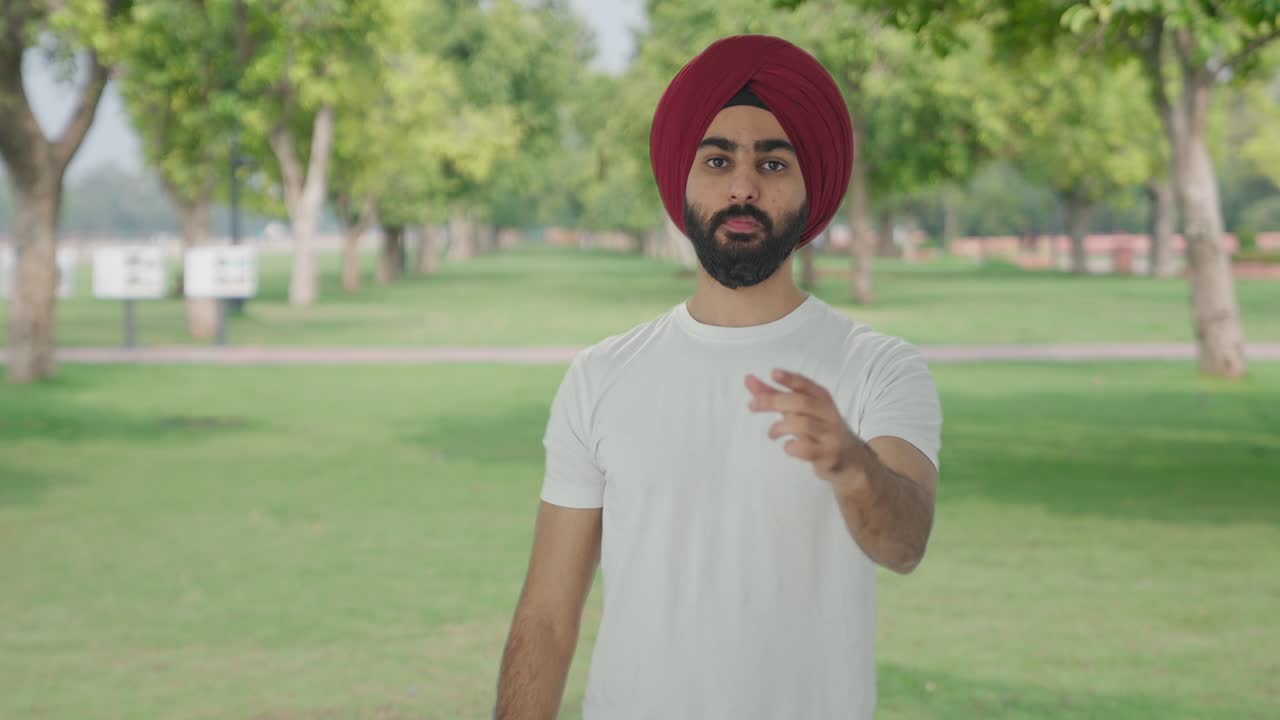 Uomo indiano Sikh turbato che legge notizie scioccanti al parco.
