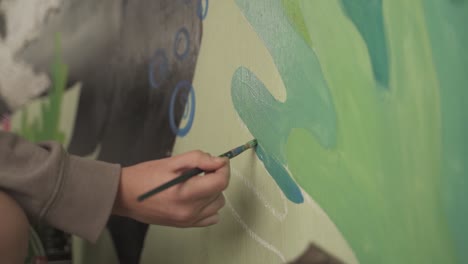 close up hand with brush painting mural on the wall,slow motion