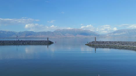 Toma-Lenta-De-La-Entrada-Del-Puerto-Deportivo-A-Saratoga-Springs-En-El-Lago-Utah-Entre-Las-Paredes-Rocosas-Del-Puerto-Deportivo-Con-Montañas-Iluminadas-Por-El-Sol-En-El-Fondo