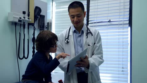 Young-asian-male-doctor-and-caucasian-boy-patient-using-digital-tablet-in-the-clinic-4k