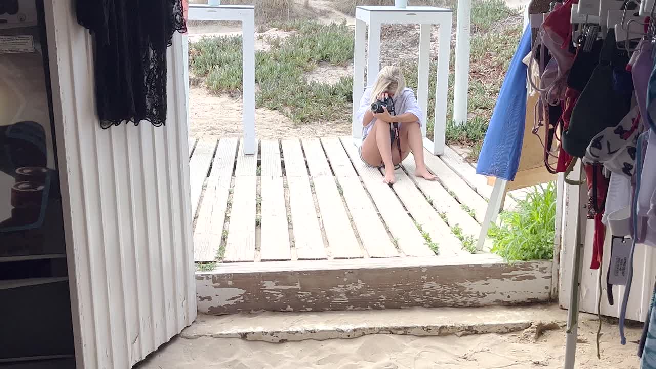 전문적인 여성 사진작가 는 해변 근처 에서 사진 을 찍기 위해 완벽 한 각도 를 찾고 있으며, 이상적 인  ⁇  을 찾기 위해 세부 사항 에 세심 한 주의 를 기울이고 있다