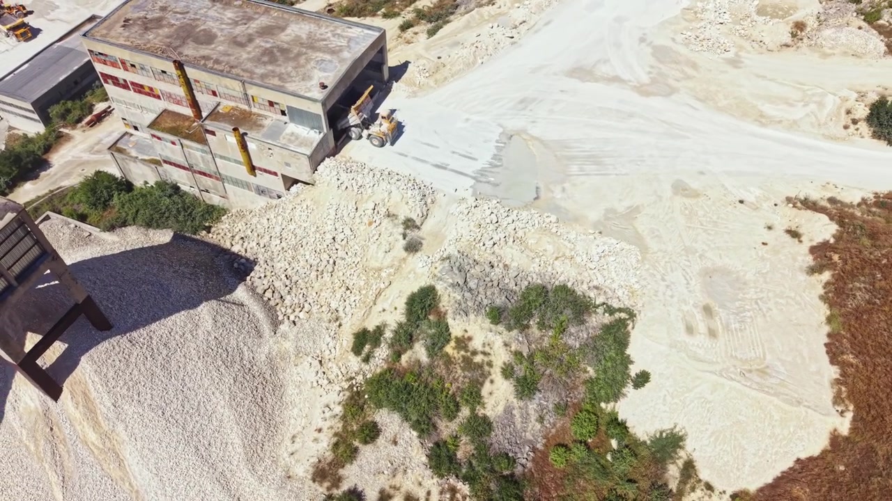 Quarry site with machinery and rock piles during daytime in an open area