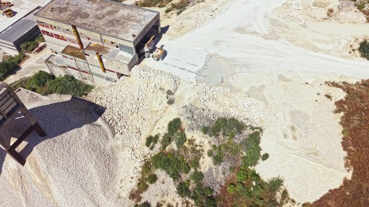 Quarry site with machinery and rock piles during daytime in an open area