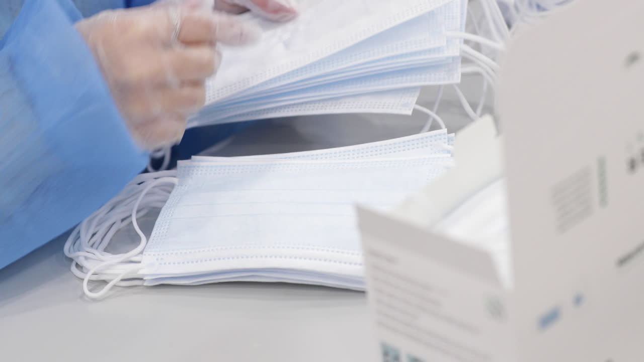 생산 기계에서 의료용 마스크를 세는 장갑을 끼고 있는 공장 노동자