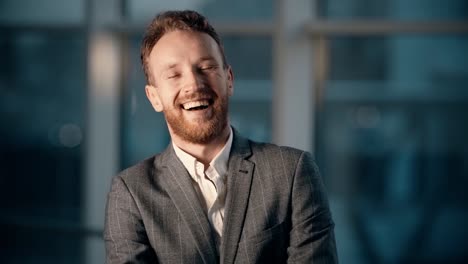 close-up-portrait-of-a-smiling-young-man-in-the-office-with-panoramic-windows-with-night-city-view