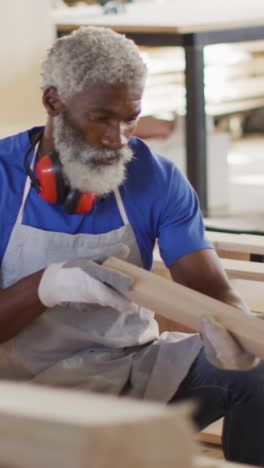 african american craftsman inspects wood in a workshop