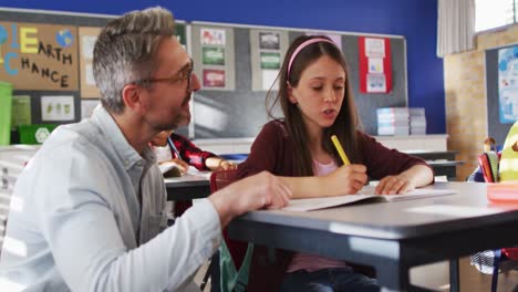 Vielfältiger,-Glücklicher-Männlicher-Lehrer,-Der-Schulmädchen-Hilft,-Während-Des-Lernens-Im-Klassenzimmer-Zu-Sitzen