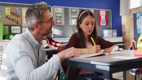 diverso maestro feliz ayudando a una escolar sentada en el aula durante el aprendizaje