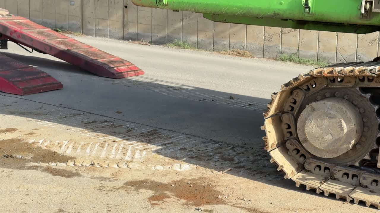 O momento em que uma máquina de construção é carregada ou descarregada de um caminhão de transporte. Construção e logística.