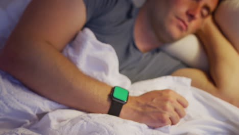 Die-Kamera-Zoomt-Auf-Einen-Mann-Heran,-Der-Im-Bett-Schläft-Und-Eine-Smartwatch-Trägt