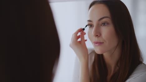 mujer aplicando máscara delante del espejo