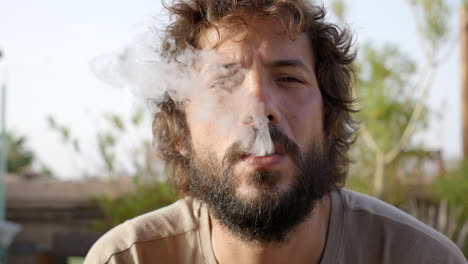 joven barbudo disfrutando de fumar un cigarrillo electrónico