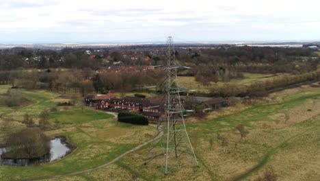 aerial orbit view across electricity distribution power pylon overlooking british parkland countryside