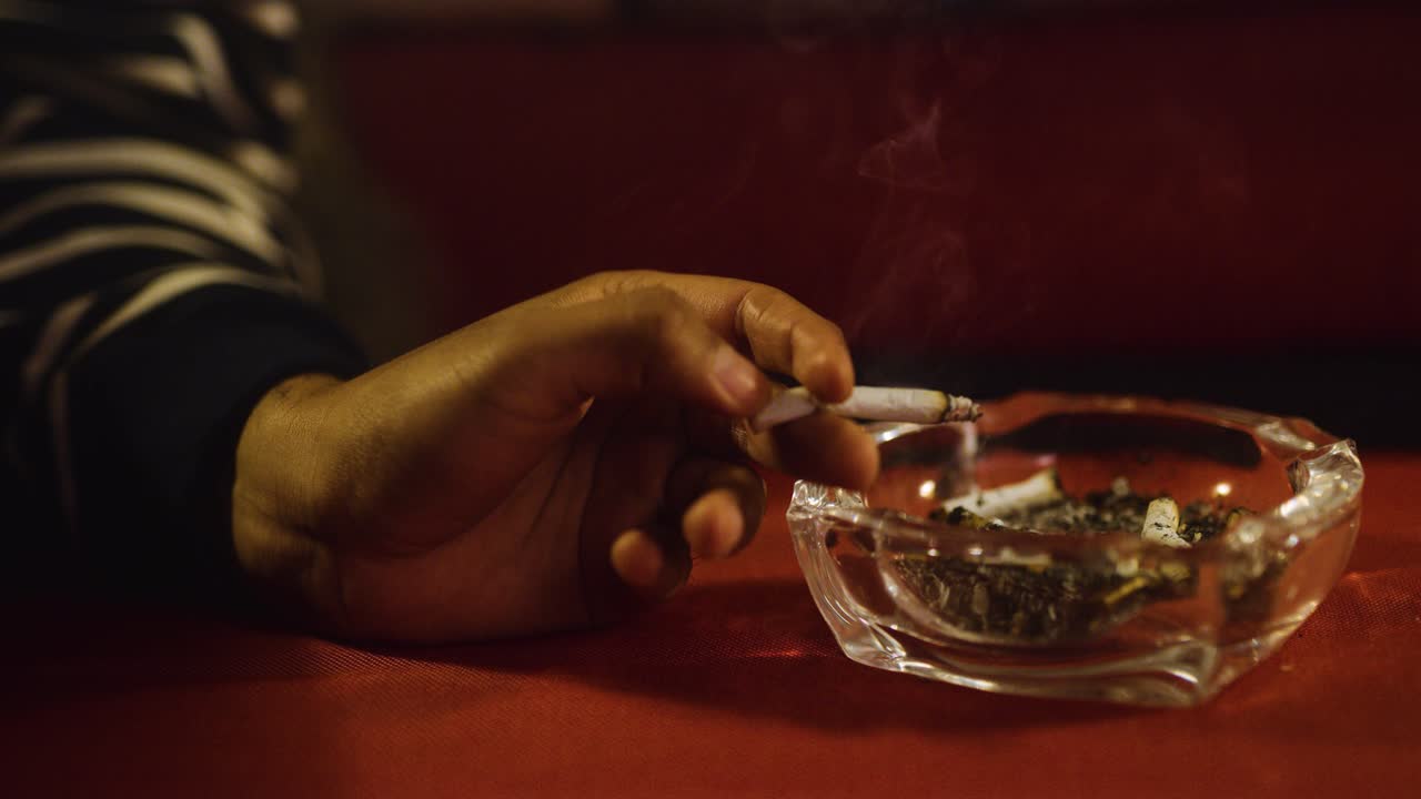 Hand smokes cigarette on couch