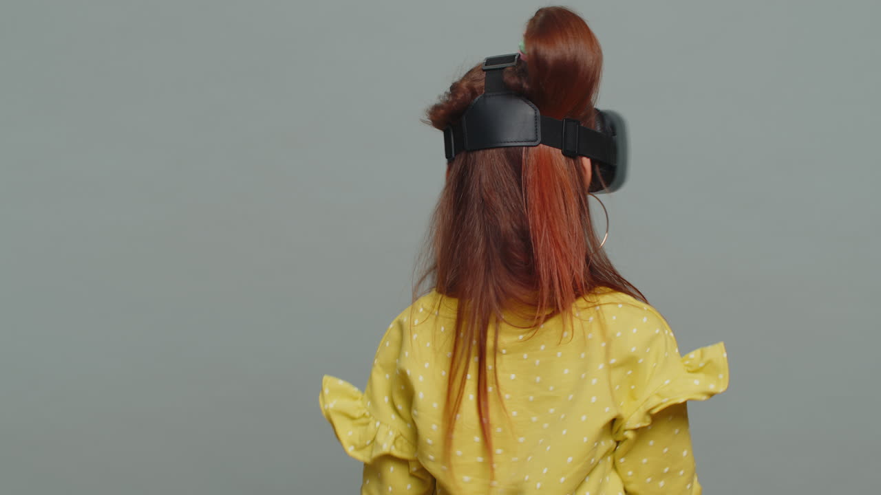 Child kid girl using headset helmet app to play simulation game watching virtual reality 3d video