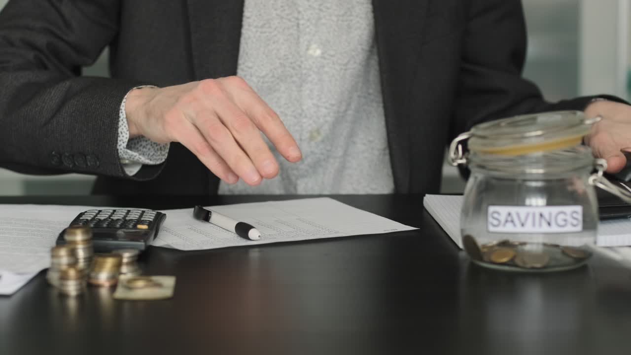 Hombre sacando dinero de una cartera en el escritorio.