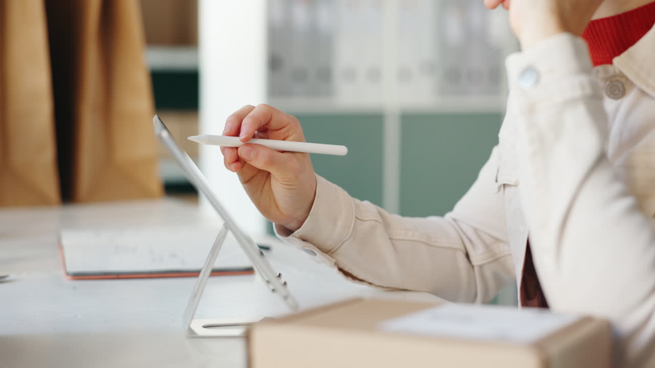 Woman using tablet to manage her online small business and pack orders for delivery