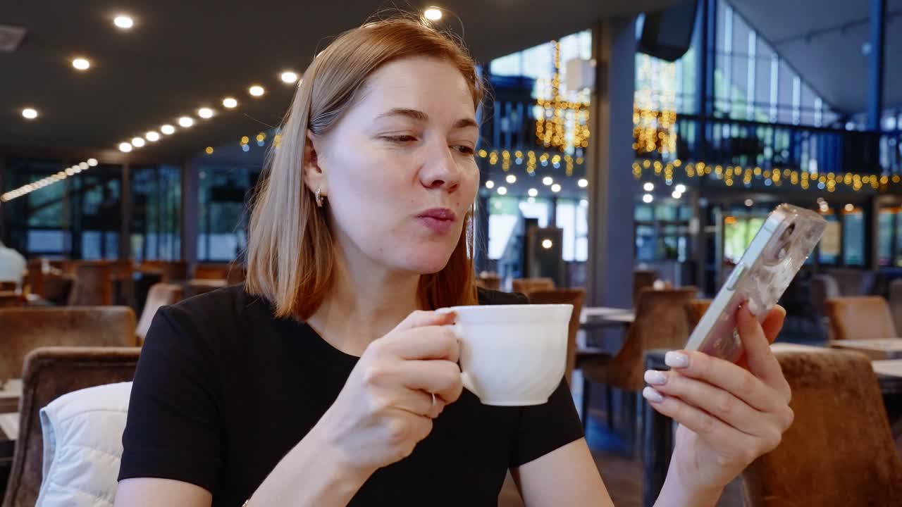 Woman in Cafe Using Smartphone While Drinking Coffee