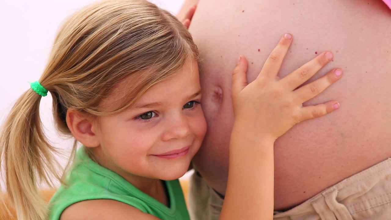 엄마의 임신 배를 듣는 어린 소녀