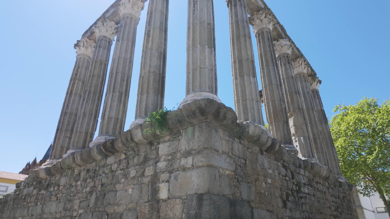 Ruined roman temple columns under blue sky in évora portugal