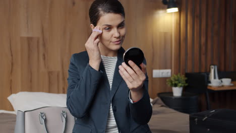 woman applying makeup in a hotel room