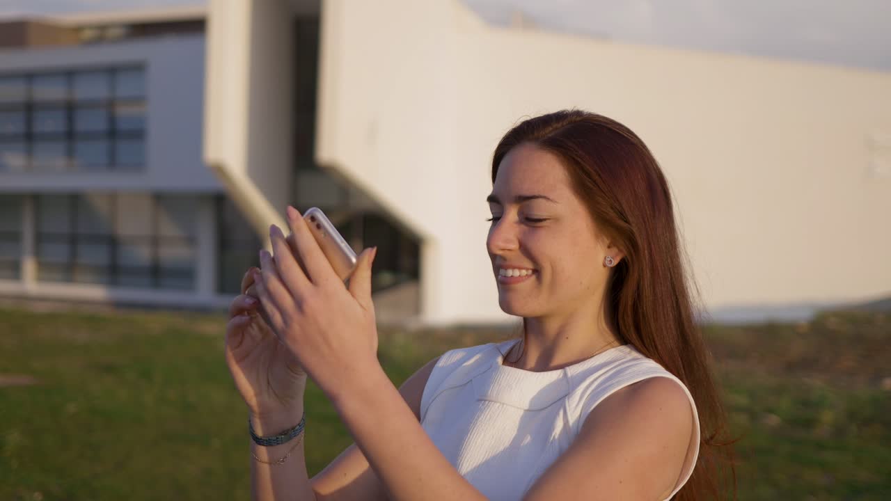 Beautiful young woman with long hair taking selfie during sunset.