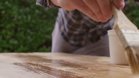 person painting a wooden table outdoor
