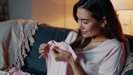 pregnant woman looking at baby clothes