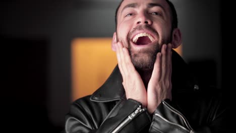 handsome bearded man in jacket gesticulates and laughs into camera, close up