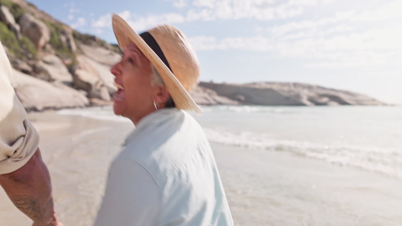 시니어 커플이 해변에서 손을 잡고 달리고 있습니다.