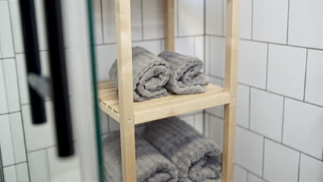 grey towels on a wooden bathroom shelf, dolly shot