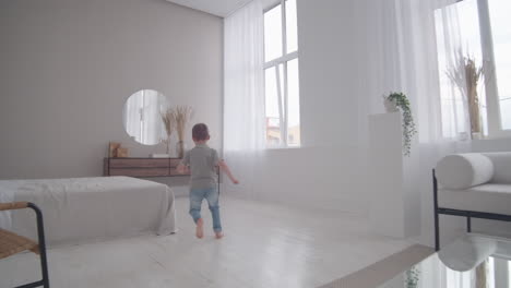 mom and son have fun playing catch-up at home in a white interior. run around the house with your child and play hide and seek