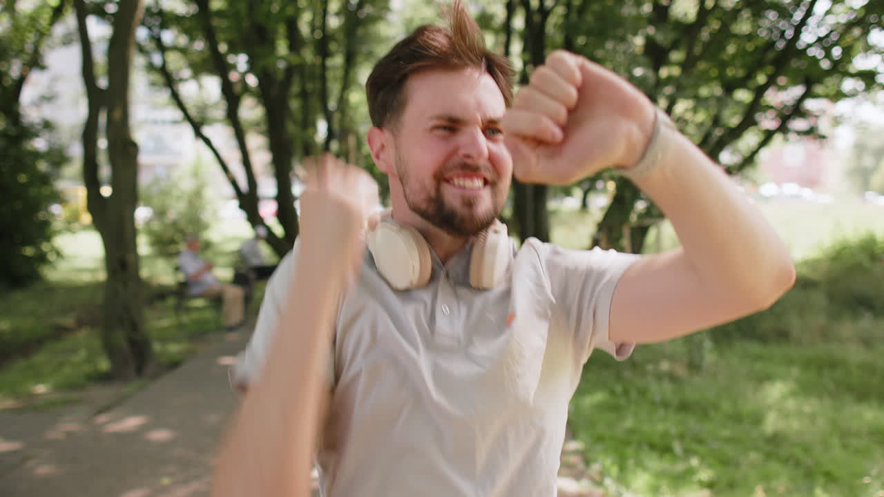 Happy runner man jogging in city park looking at smartwatch checking result celebrating success