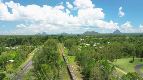 Queensland-Eisenbahn-Durch-Ländliche-Landschaft-Mit-Malerischer-Bergkulisse,-4K-Drohnenansicht