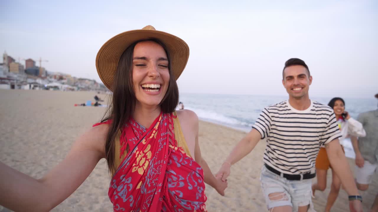 grupo feliz de jóvenes divirtiéndose en la playa. amigos alegres corren de la mano disfrutando de la puesta de sol de verano. concepto de tiempo libre y comunidad.
