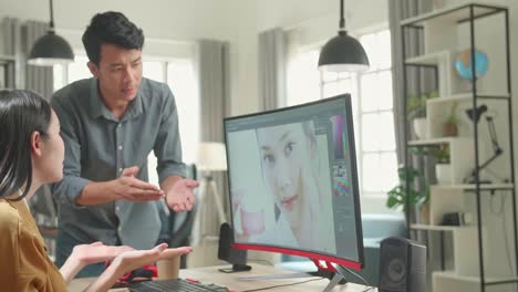 Asian Male And Female Professional Editors Arguing While Working In Photo Editing App / Software On A Personal Computer. Photo Editors Retouching Photos Of A Beautiful Girl